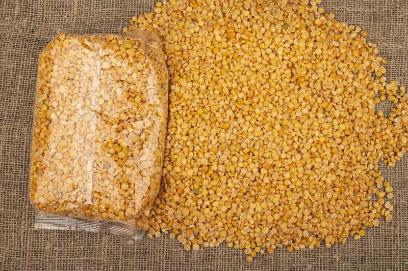 YelloYellow split peas in a plastic bag and cereal in bulk on a background of burlap with a rough texture. Traditional cereals for. Yellow split peas in a royalty free stock photos