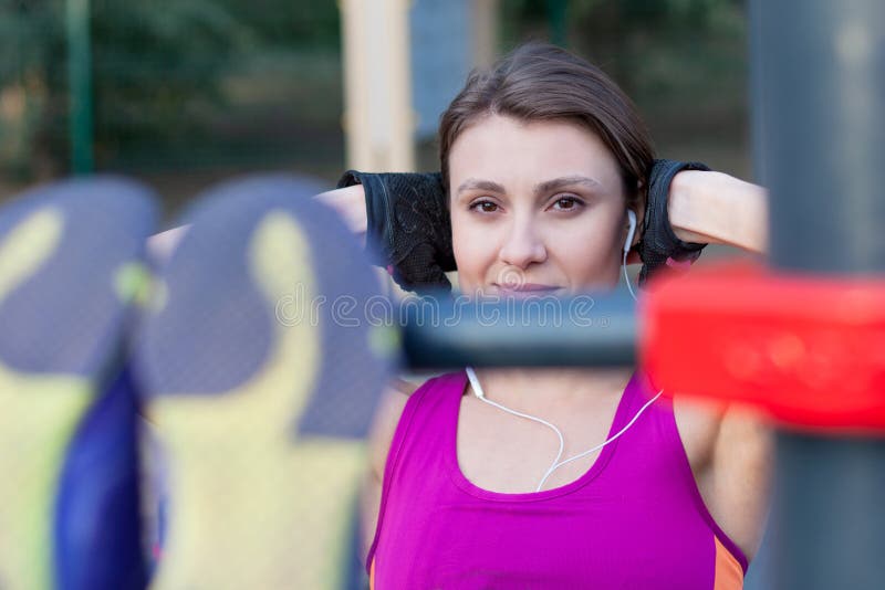 Young caucasian woman workouts on the park sports ground, making abdominal training. Bright sportswear, protective gloves, white e stock photos