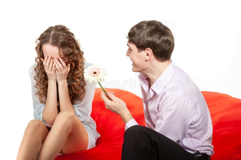 A young man gives a young offended woman with curly hair a flower as a sign of reconciliation. stock images