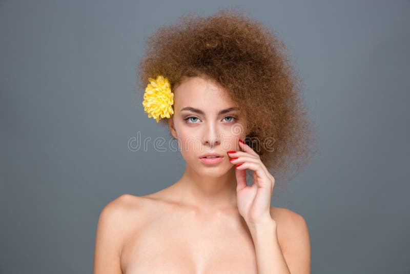 Young sensual curly woman with yellow flower in her hair stock image