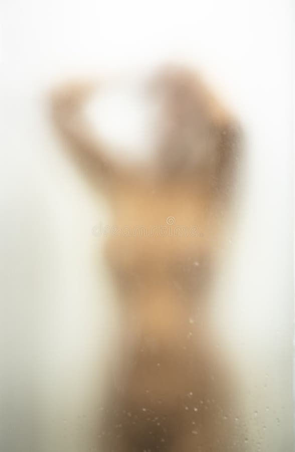 Young Woman Taking Shower or Junub Bath After washing Her Hair. Concept of Health, Hygiene and self Care. Shoot Through Blurry Iced Bathroom Glass royalty free stock photo