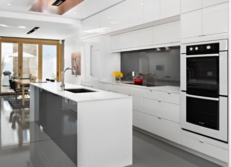 Кухня белого цвета с островом и встроенной техникой