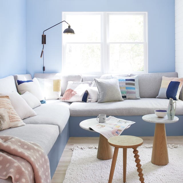 Light blue living room walls frame a large gray banquette