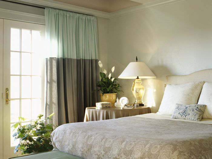 Двухцветные шторы в спальне с лампой на тумбочке